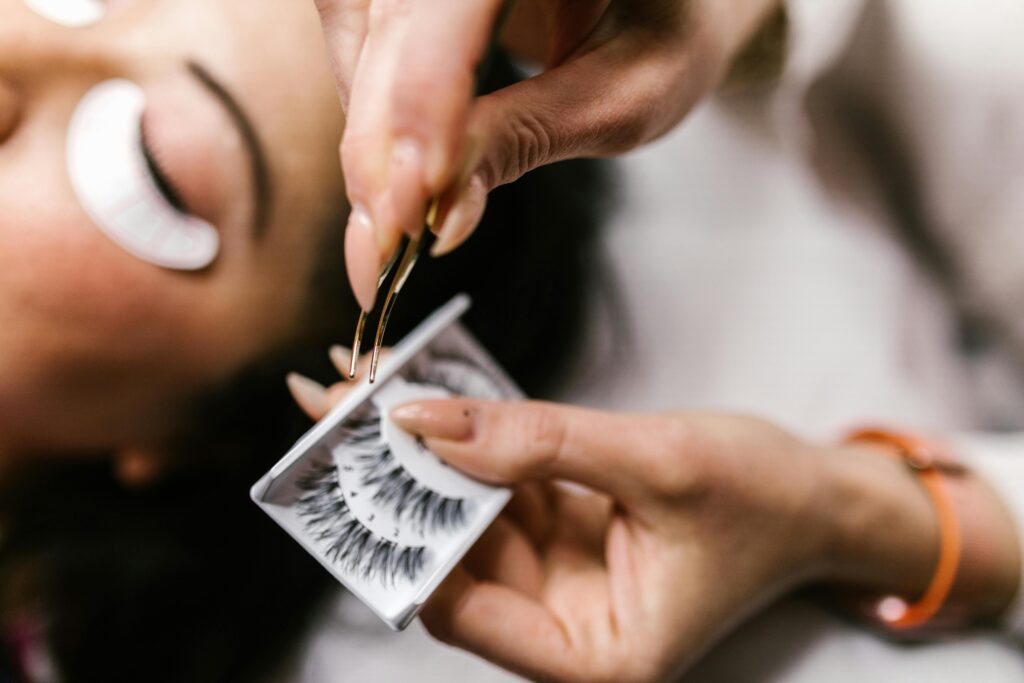 Close-up of applying false eyelashes with tweezers during a beauty treatment.